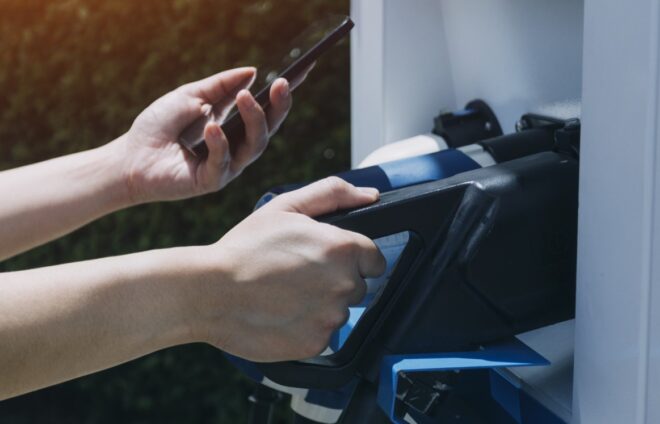 Hand plugging in a charger in an electric car socket.Electric car or ev is charging at station